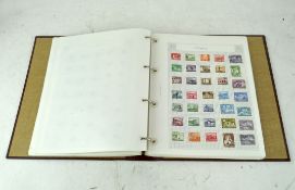 A red leatherette bound stamp album, containing a quantity of stamps,