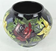 A small contemporary dark blue Moorcroft vase decorated with daffodils, roses and thistles,
