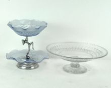 A glass two-tier cake stand with fluted rims, supported with a female figure to the centre,