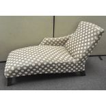 A contemporary chaise longue, upholstered in a polka dot fabric, raised on four feet,