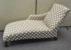 A contemporary chaise longue, upholstered in a polka dot fabric, raised on four feet,