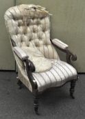 A Victorian button back armchair with scroll arms and turned legs on casters,