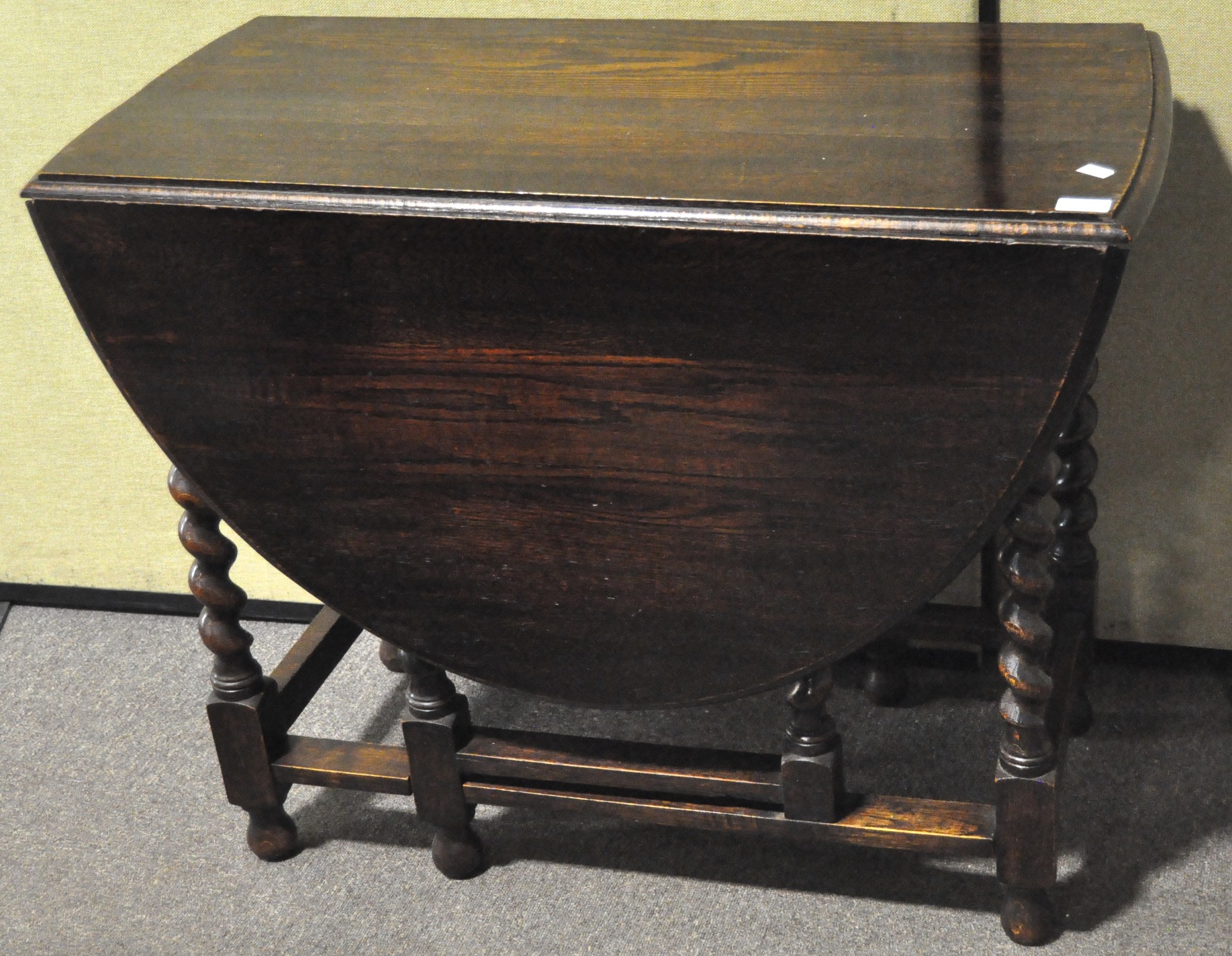 A stained oak gate leg table, on barley twist legs,