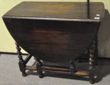 A stained oak gate leg table, on barley twist legs,