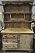 An early 20th century pine kitchen dresser with panelled back and two fixed shelves