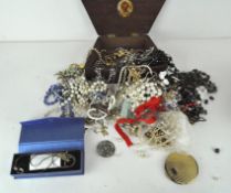 A large group of costume jewellery including necklaces, brooches, loose beads, a vintage compact,