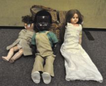 A vintage wicker picnic basket containing various dolls, including a Heubach-Koppelsdorf doll.