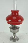 A vintage Super Aladdin oil lamp with original red and white glass shade and clear funnel