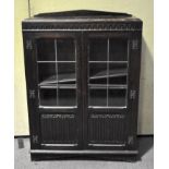 A early 20th century glazed oak cabinet with twin leaded glazed doors and adjustable shelves,