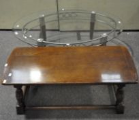 A modern glass topped oval coffee table with metal and wood legs,