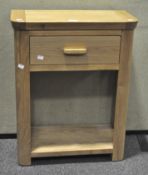A modern light oak side table with single drawer and lower shelf