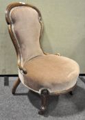 A Victorian walnut nursing chair raised on cabriole supports and casters, upholstered in pale pink,