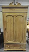 An early 20th century pine wardrobe with broken pediment to the top and a single wide door above