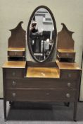 A mid-century dressing table with oval swing mirror above six drawers, with cross grain detailing,