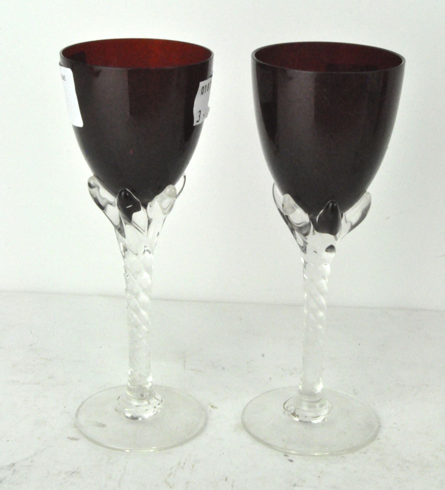 A pair of crimson coloured wine glasses, with spiral stems,