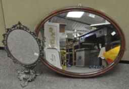 A vintage oval wall mirror in a wood frame,