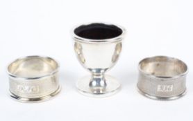 A silver christening set, including an egg-cup and two engine turned napkin rings engraved RJC,