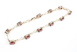 A yellow metal bracelet set with oval garnets and inter-spaced with figure of eight links.