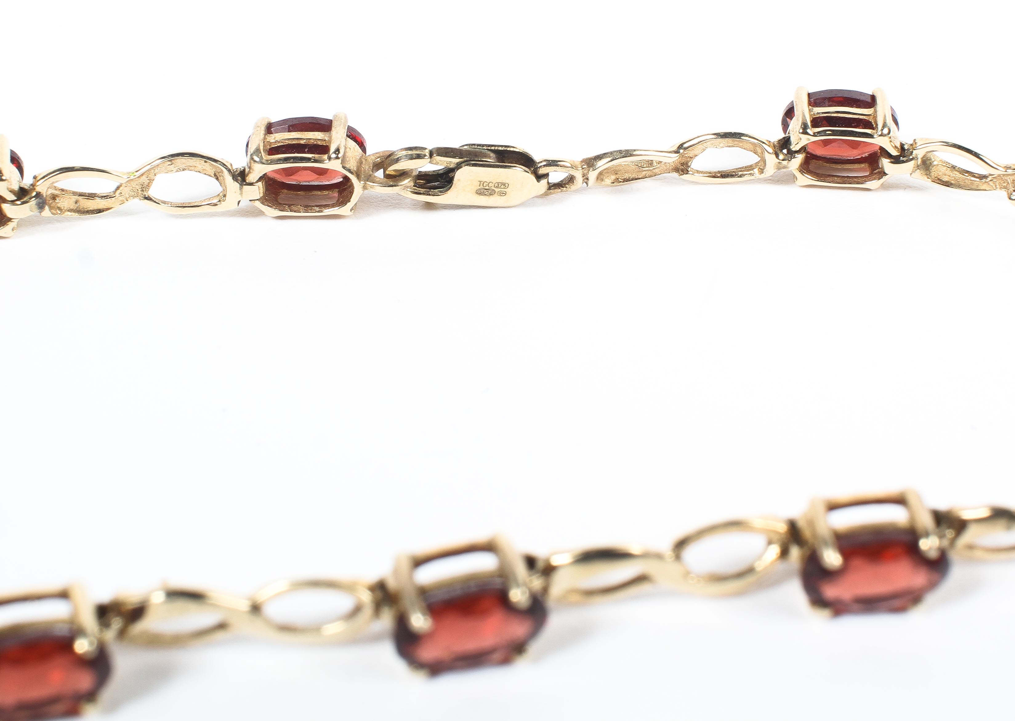 A yellow metal bracelet set with oval garnets and inter-spaced with figure of eight links. - Image 2 of 2