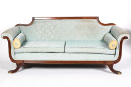 A Regency style mahogany sofa, the padded back above scrolled arms, cushion seat and splayed legs,