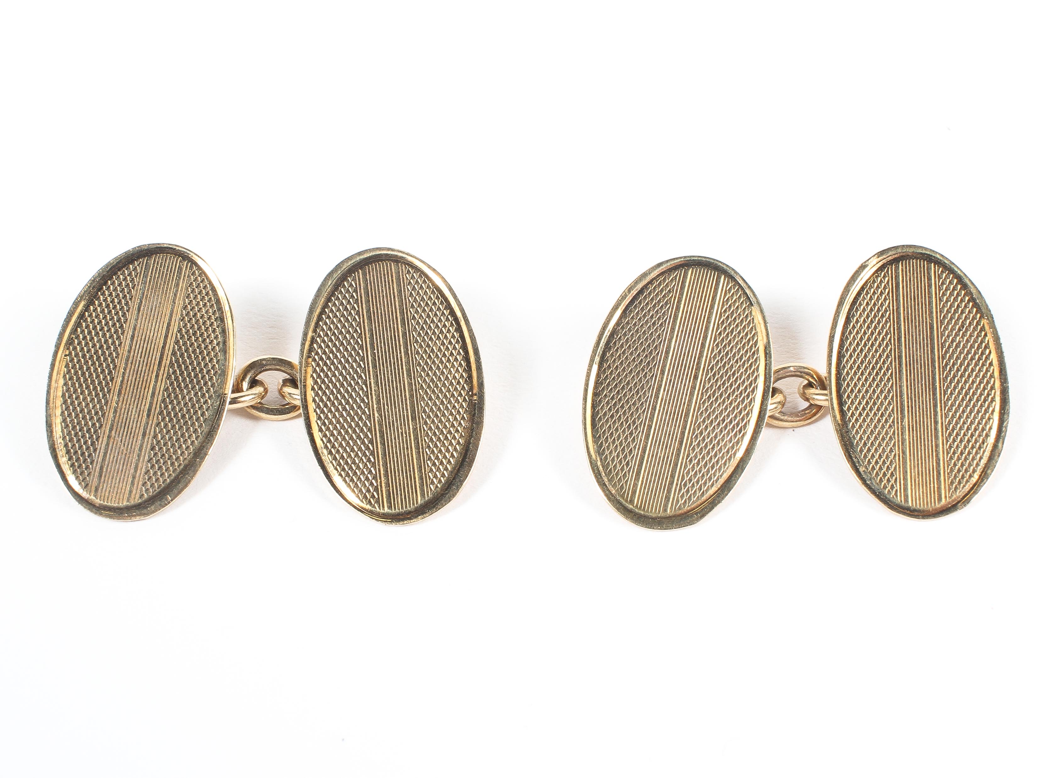 A yellow metal pair of chain link cufflinks with oval terminals having engine turned design.