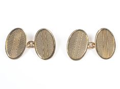 A yellow metal pair of chain link cufflinks with oval terminals having engine turned design.