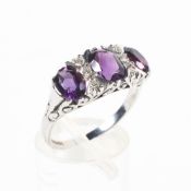 A white metal half hoop ring set with three oval cut amethysts