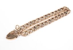 A yellow metal curb link bracelet with padlock clasp and fitted safety chain.