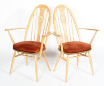 A pair of Ercol swan back beech framed armchairs, with red fabric cushions, on tapering legs,