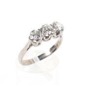 A white metal three stone ring set with round brilliant cut diamonds