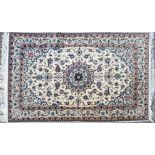 A Nain rug, a central roundel inside scrolling foliage on a cream ground with a triple border,