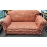 A drop end sofa supported on bun feet and casters, with removable arm covers,