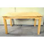 A contemporary pine kitchen table, raised on four square legs,