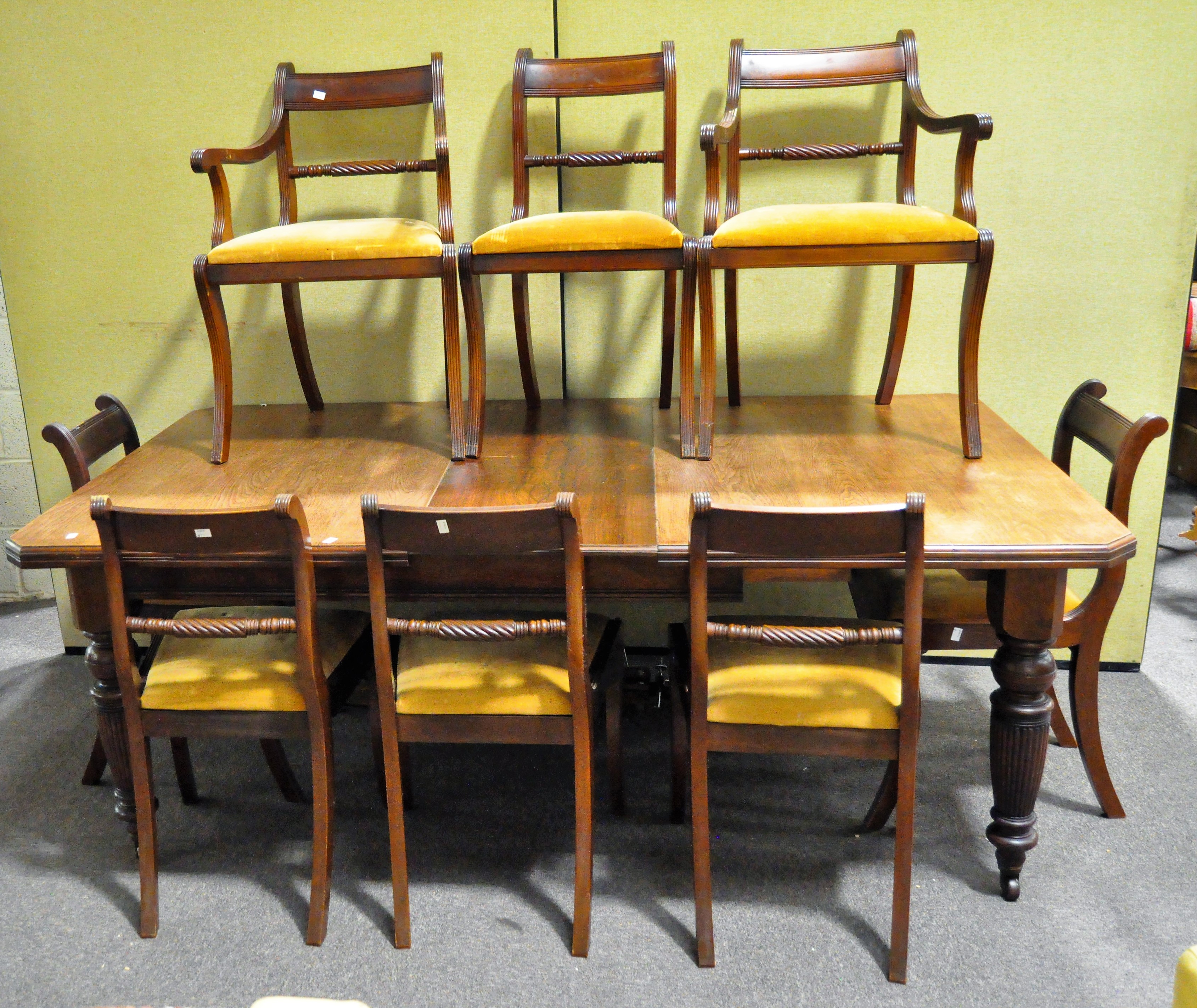 A mahogany three leaf dining table on tunred and fluted supports and castors and eight chairs