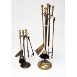 Two early 20th Century brass fireside companion sets, each with brushes, tongs and shovels,