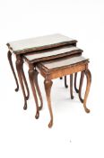 A nest of three tables with walnut veneer tops, decorative carving to edge and legs,