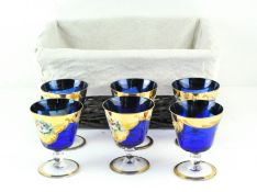 A set of six mid-blue Murano glass cups, on circular bases, all with gilt and floral decoration,