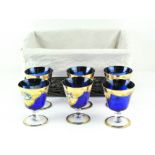 A set of six mid-blue Murano glass cups, on circular bases, all with gilt and floral decoration,