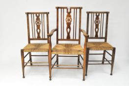 Three early 20th century rush-seated,wheel back chairs on lightly tapered legs and bun feet,