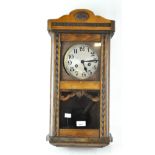 A vintage Vienna-style wall clock with face and pendulum visible behind glass,