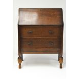 A mid century oak bureau, the front opening to reveal compartmented interior, over two long drawers,