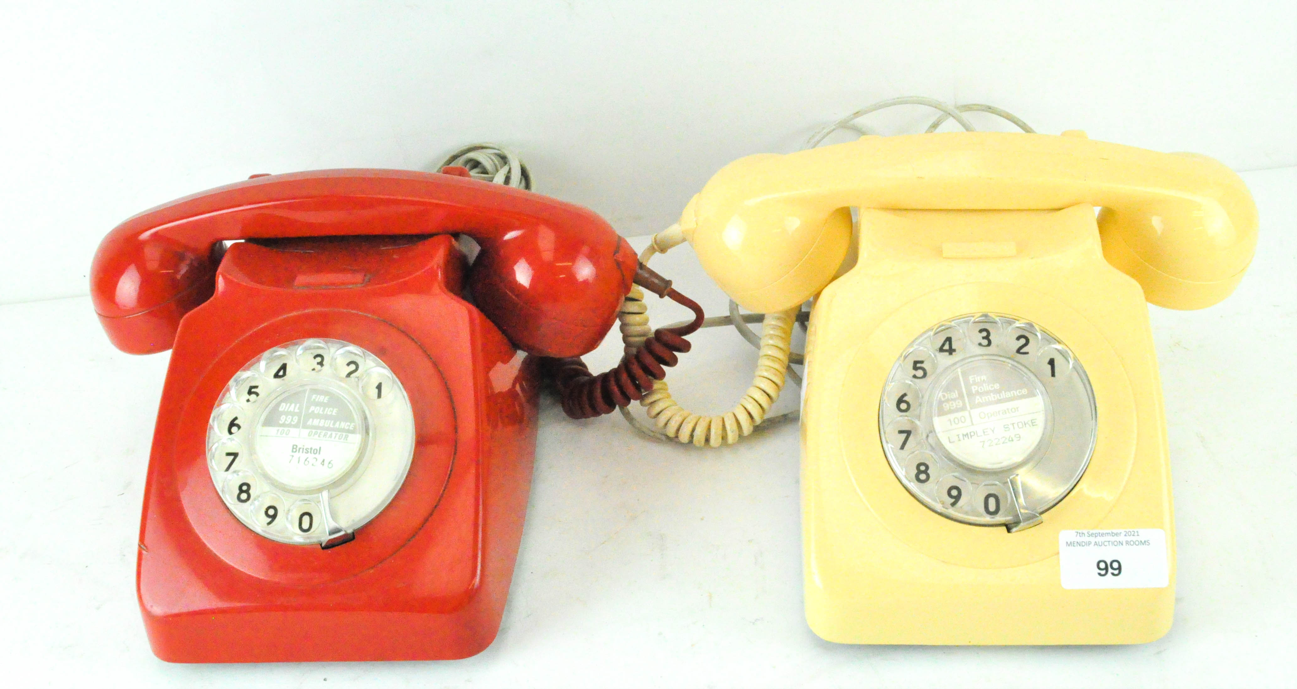 Two vintage telephones, in red and cream cases,