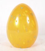 A glass 'egg' lampshade, in orange with yellow and green speckled decoration,