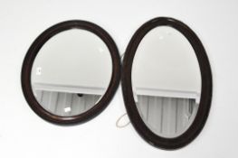 Two late 19th/early 20th century mahogany framed mirrors of oval form, each with bevelled edge,