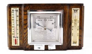 An Art Deco wall hanging oak cased barometer, flanked by a thermometer and storm glass,