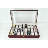 A modern watch collection box with clear top, containing a selection of wristwatches,