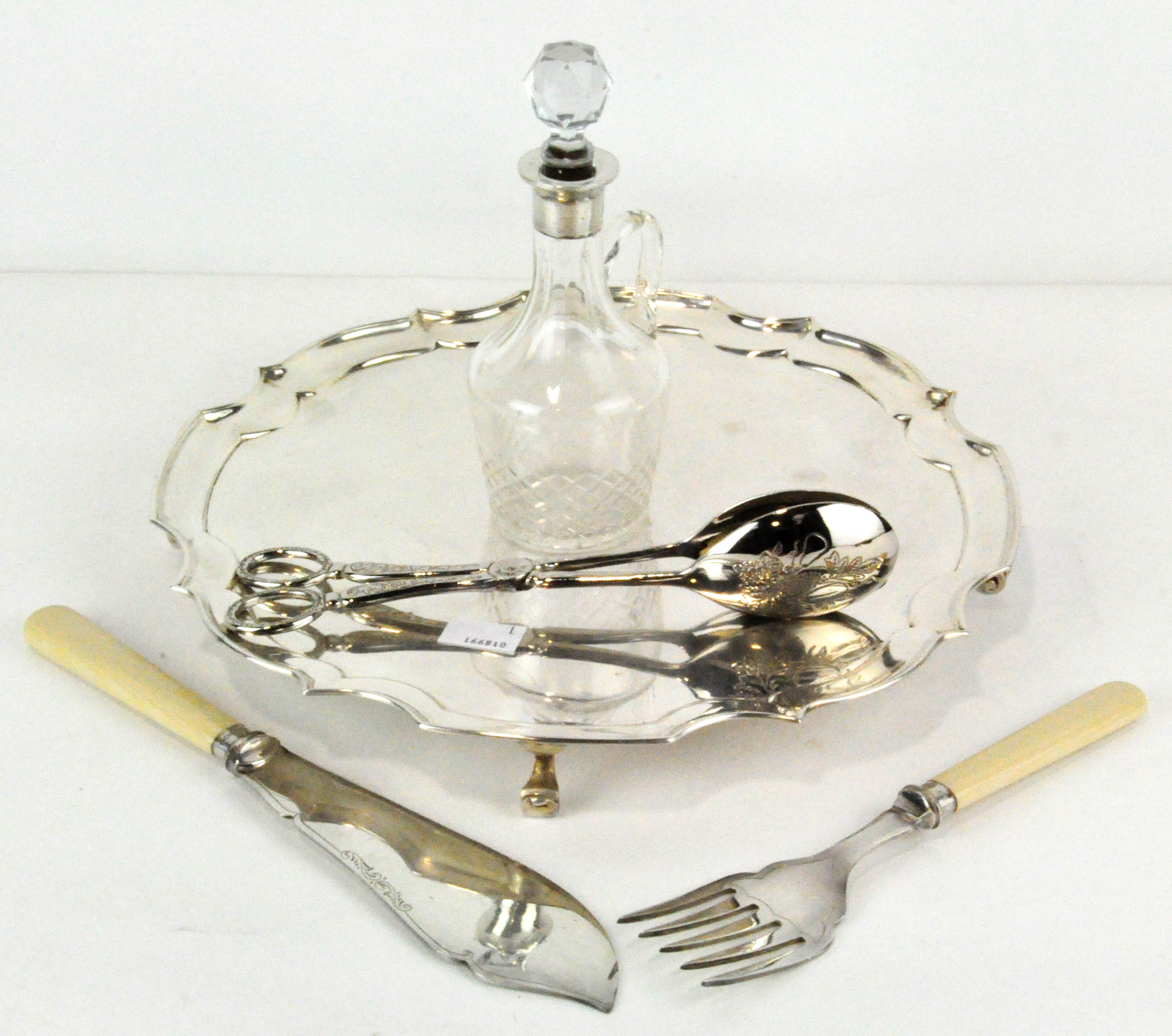 A silver topped jug with a silver rimmed knife and fork and silver plated pair of tongs and platter
