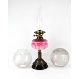 A late Victorian oil lamp, with a pink glass well,