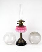 A late Victorian oil lamp, with a pink glass well,