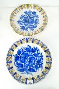 A pair of 19th Century Continental tin glazed pottery chargers, decorated with flowers and foliage,